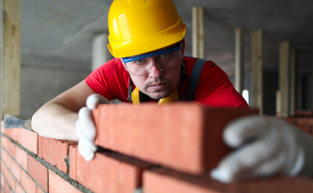 bricklayer aligning brick