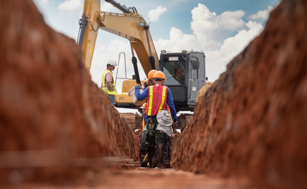 men standing in trench near excavator