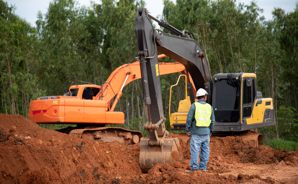 construction worker standing near two excavators
